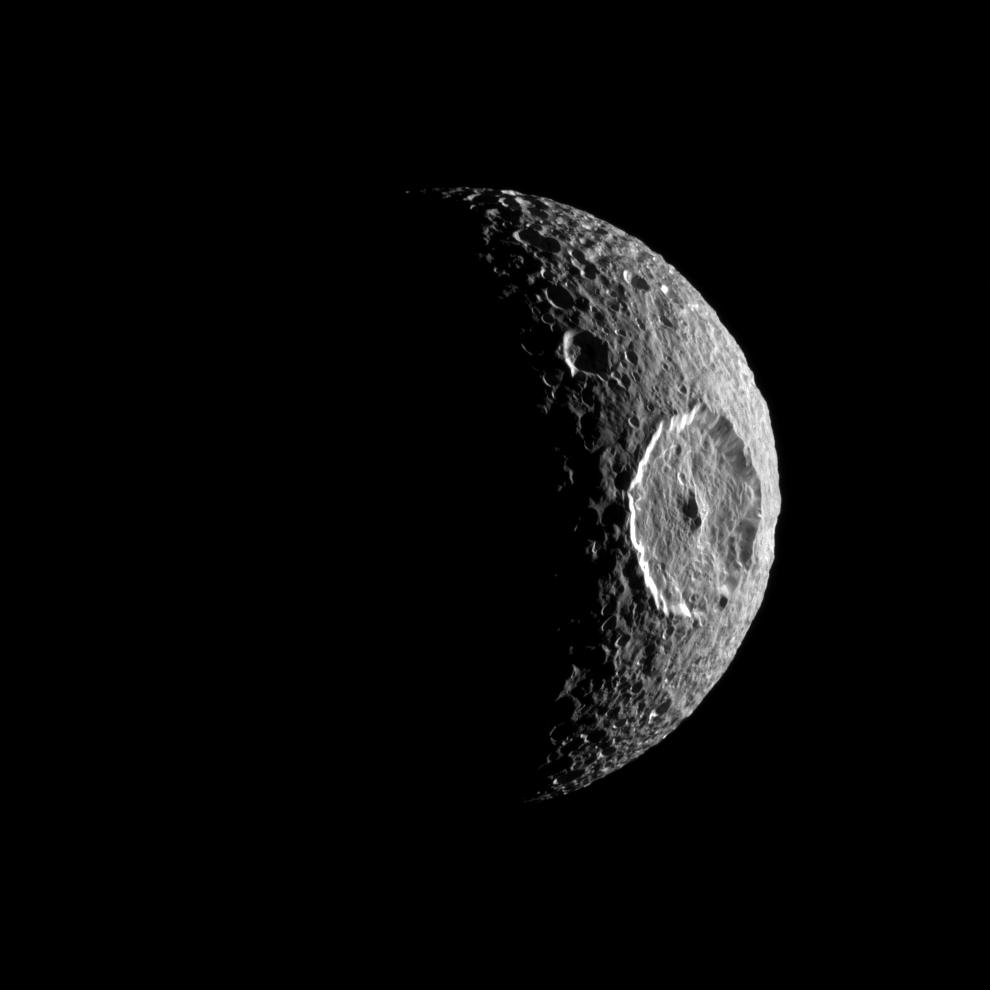 Partially-illuminated moon dominated by large impact crater.
