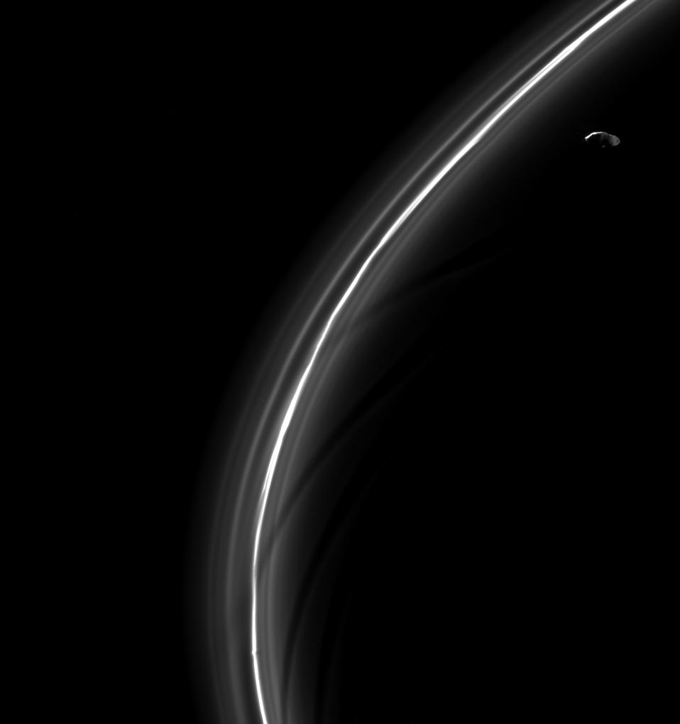 Saturn's moon Prometheus, seen here looking suspiciously blade-like, is captured near some of its sculpting in the F ring.