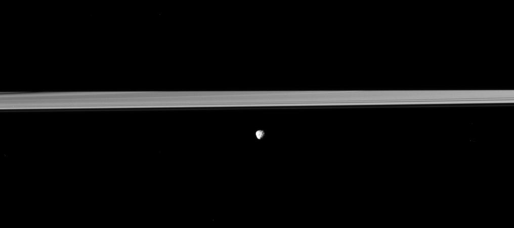 Saturn's moon Janus orbits in front of the rings, which are partially darkened by the shadow of the planet in this Cassini spacecraft view.