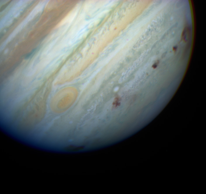 Jupiter with a line of dark impact marks along the bottom third of the planet.