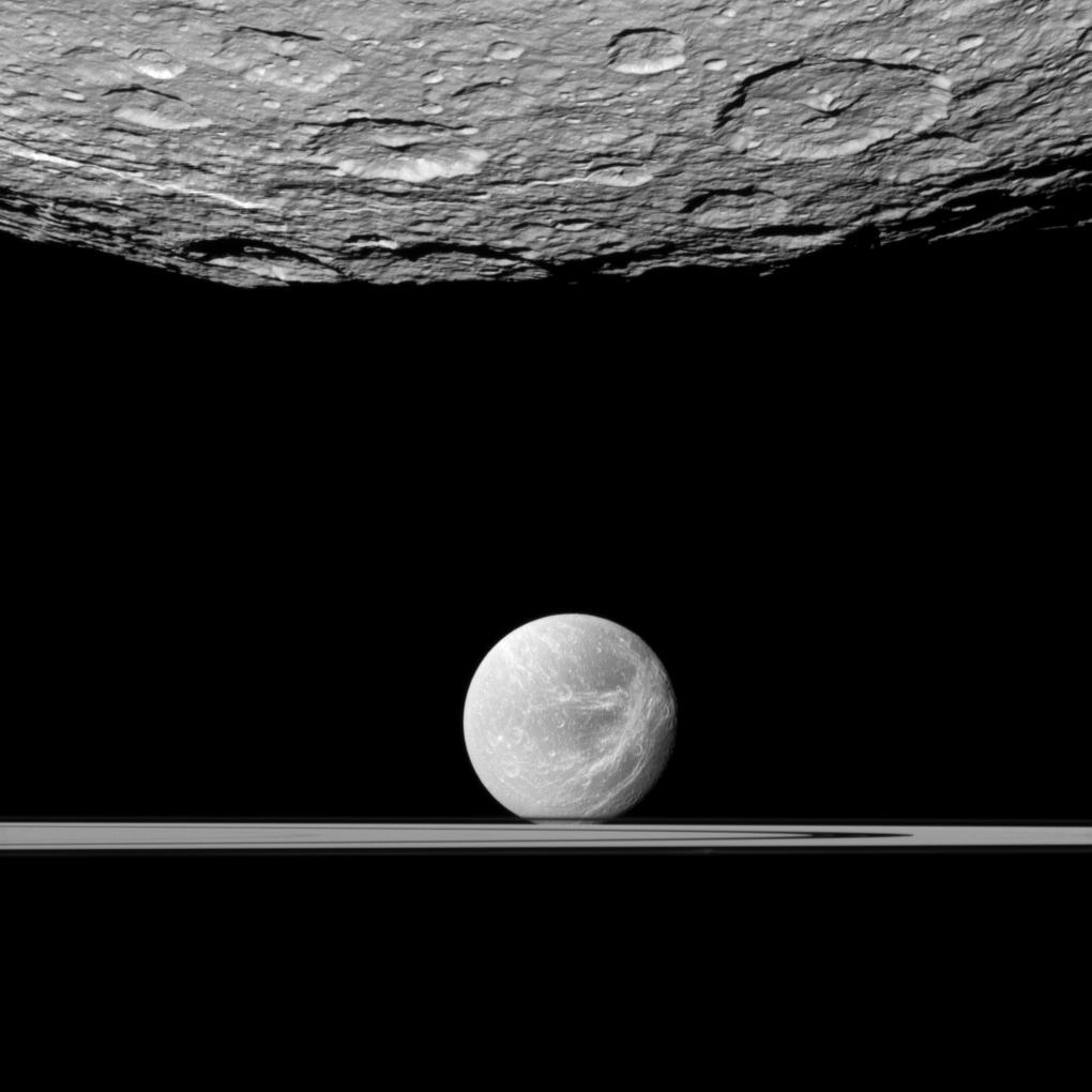 Rhea in foreground at top and Dione and the rings below