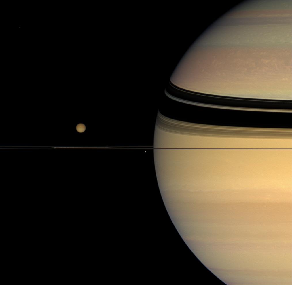 Four moons huddle near Saturn's multi-hued disk.