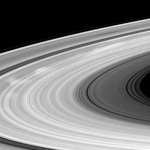 Bright spokes and the shadow of a moon grace Saturn's B ring in this Cassini spacecraft image.