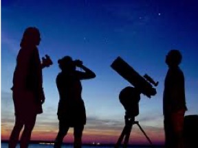 silhouette of people looking at the sky with a telescope