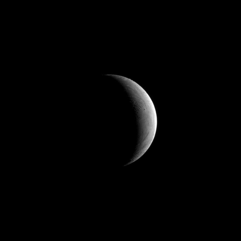 The Cassini spacecraft captures a crescent of Saturn's moon Enceladus. Lit terrain seen here is in the area between the leading hemisphere and Saturn-facing side of Enceladus. The image was taken May 10, 2011.