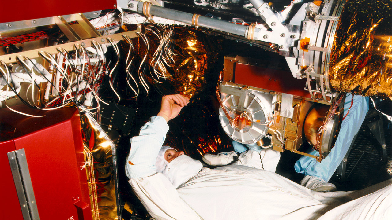 Color image of technician working on part of the Cassini spacecraft.