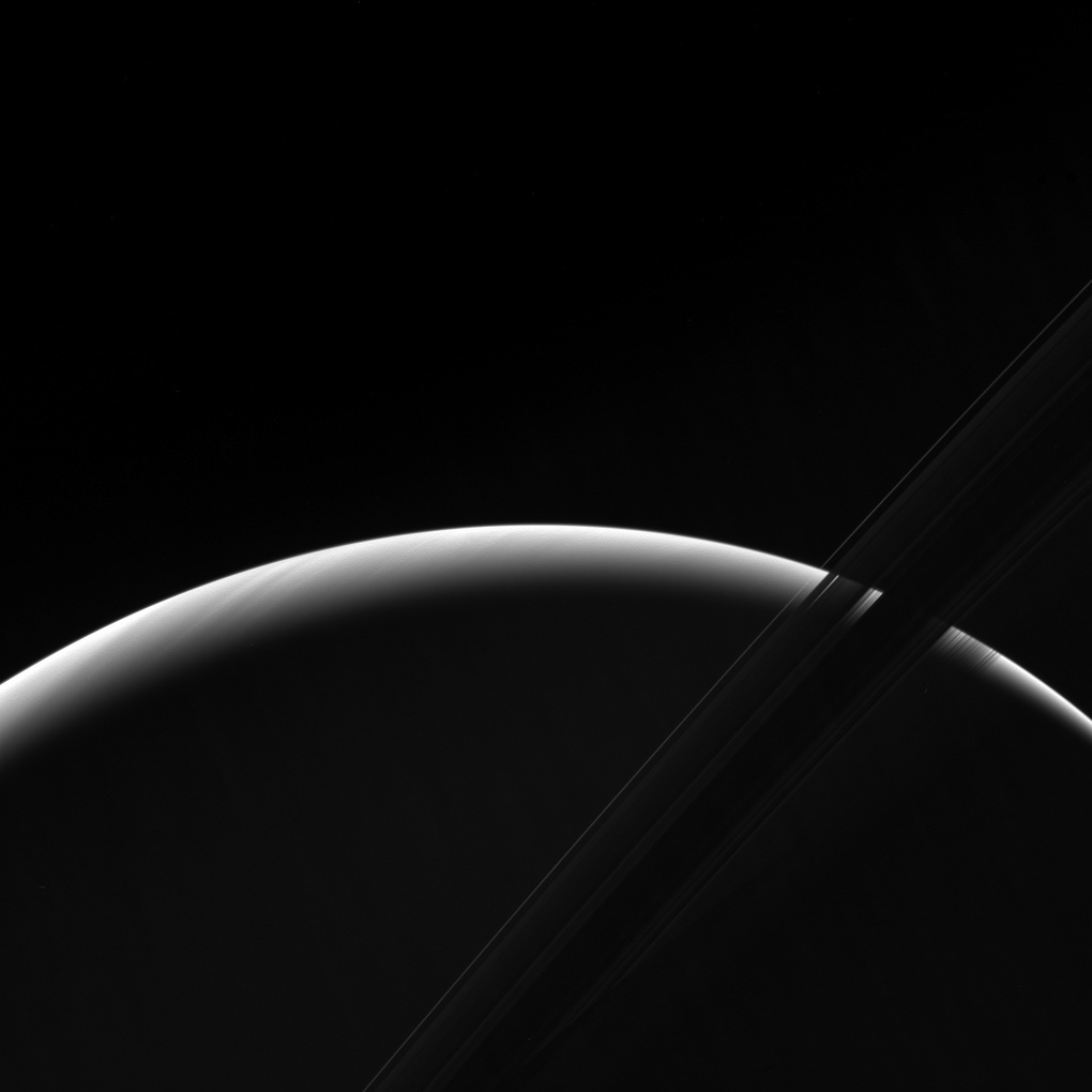 NASA's Cassini spacecraft peers toward a sliver of Saturn's sunlit atmosphere while the icy rings stretch across the foreground as a dark band.