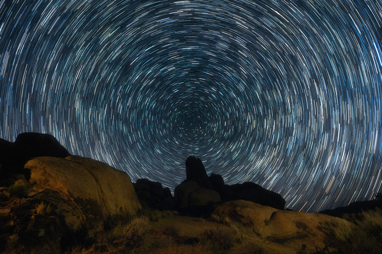 long exposure image of stars at night, capturing their circular movement around the North Star