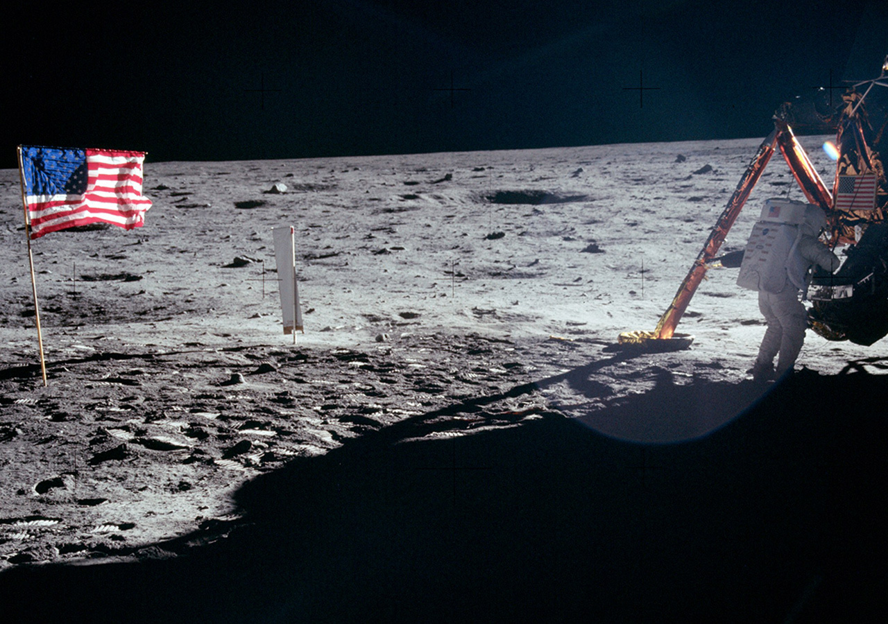 Astronaut Neil Armstrong in a white spacesuit standing on the surface of the Moon.