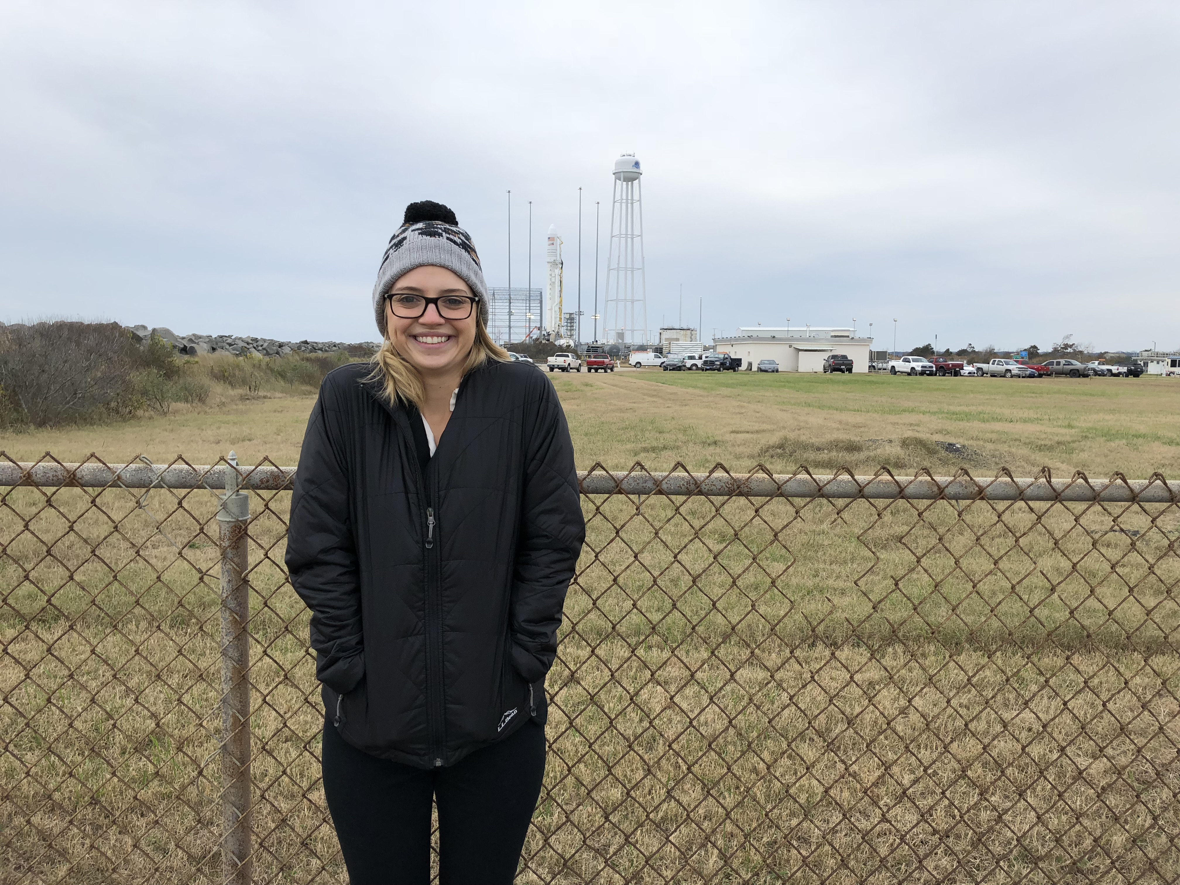 Smiling woman in front of rocket on launch pad.