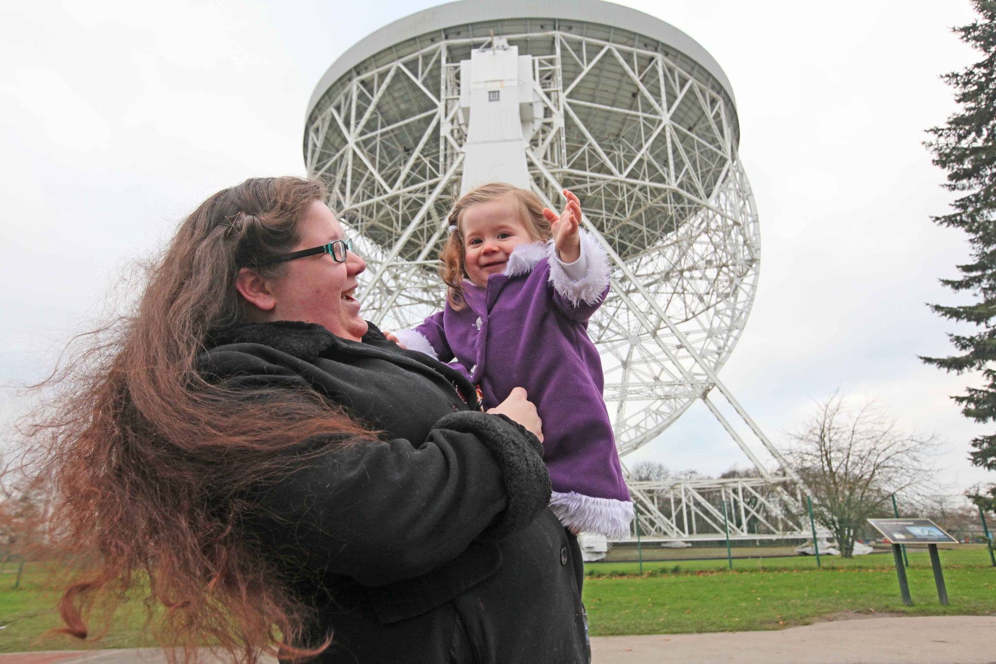 Woman holding small child in front of observatory.