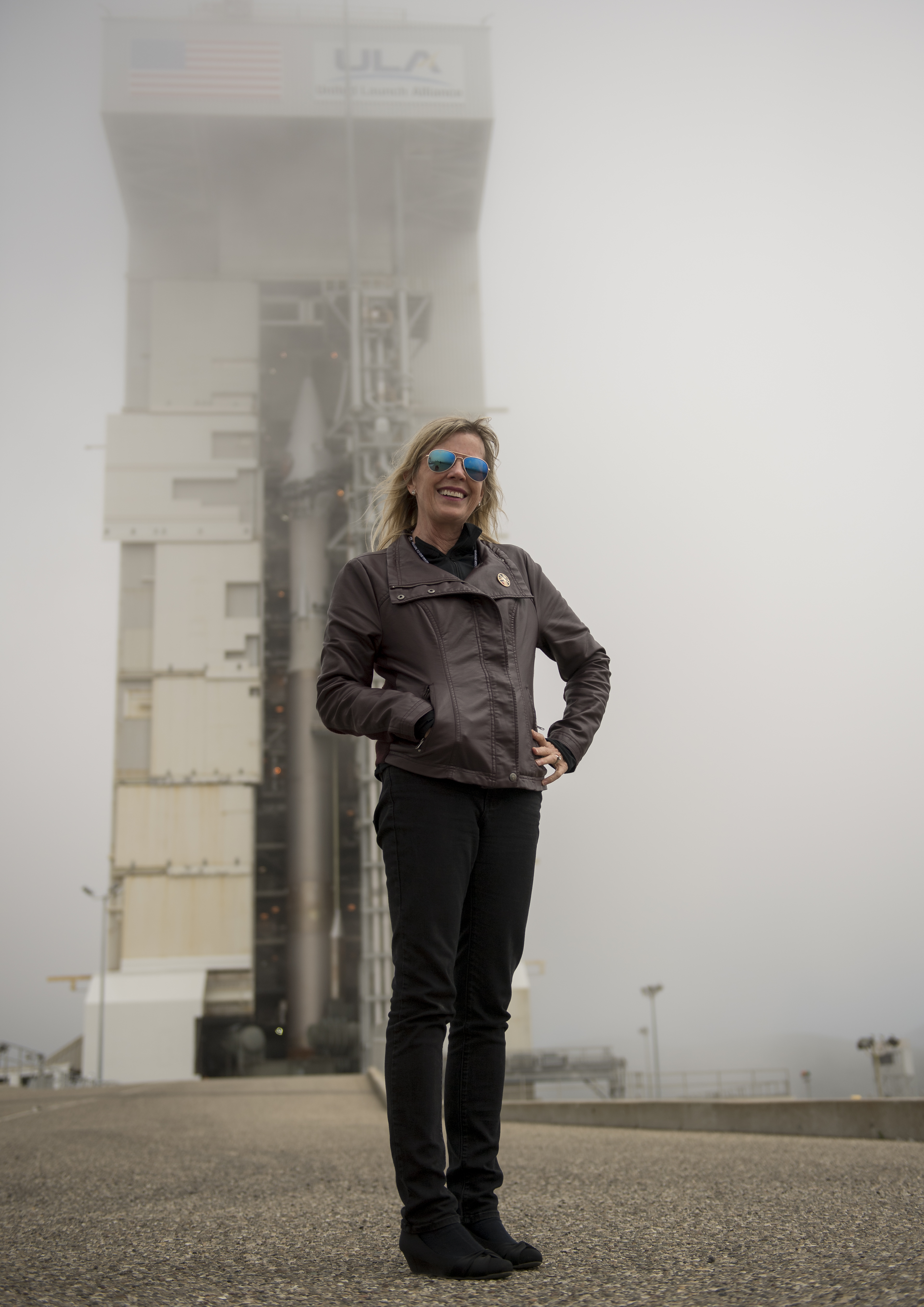 Woman standing in front of rocket on launch pad.
