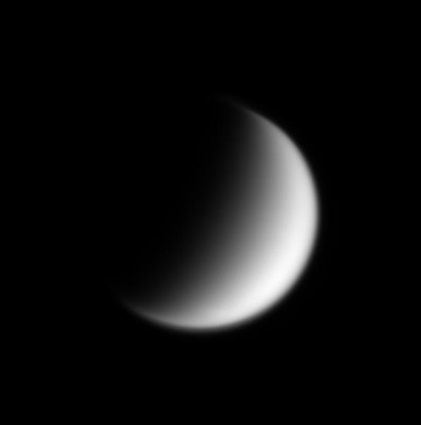 Fuzzy black and white image of the crescent of Saturn's moon Titan.