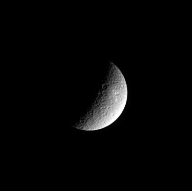 Half of Rhea's battered surface is illuminated by sunlight in this black and white image.