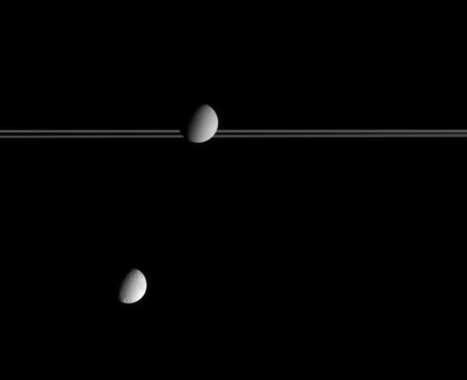 The moon Dione occults part of Saturn's distant rings while Tethys hovers below