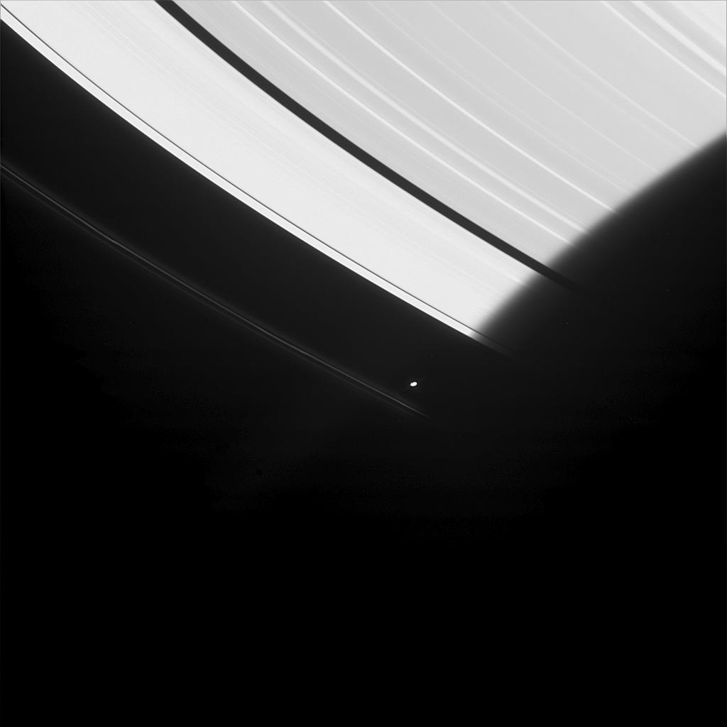 Saturn's moon Prometheus is seen here emerging from the darkness of Saturn's shadow
