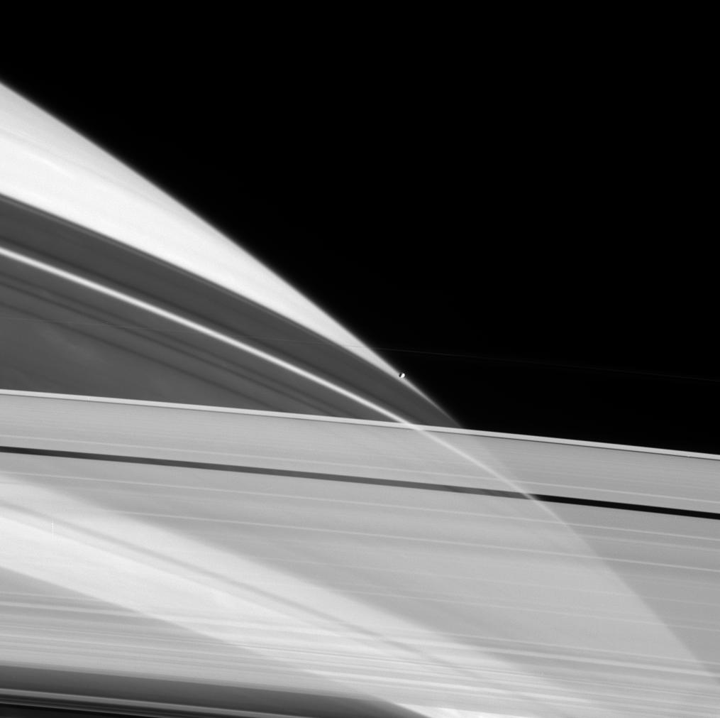 Cassini peers through the icy particles that comprise Saturn's rings as Prometheus sits perched on the planet's limb