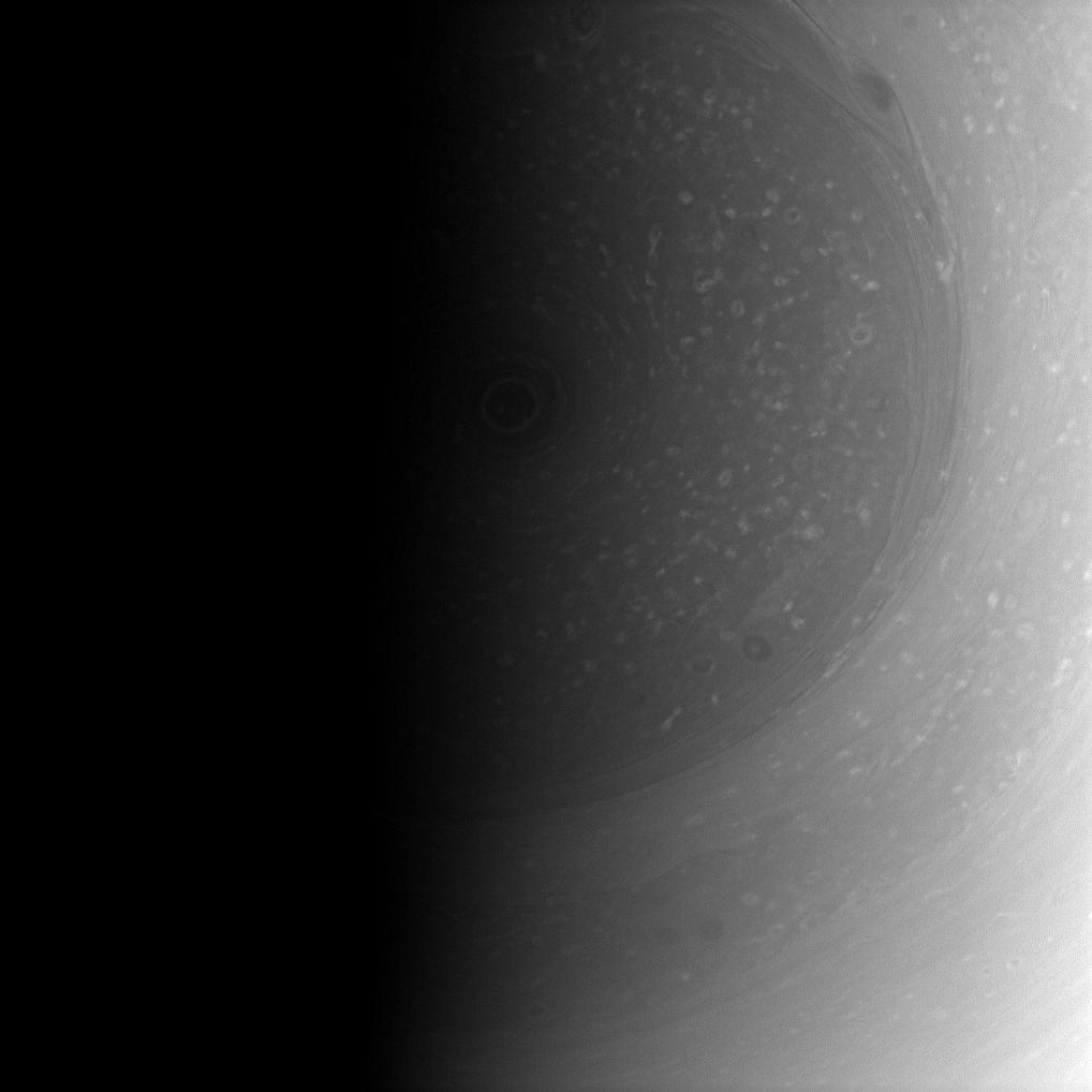 The terminator nearly covers the south pole of Saturn and its stormy vortex in darkness. 