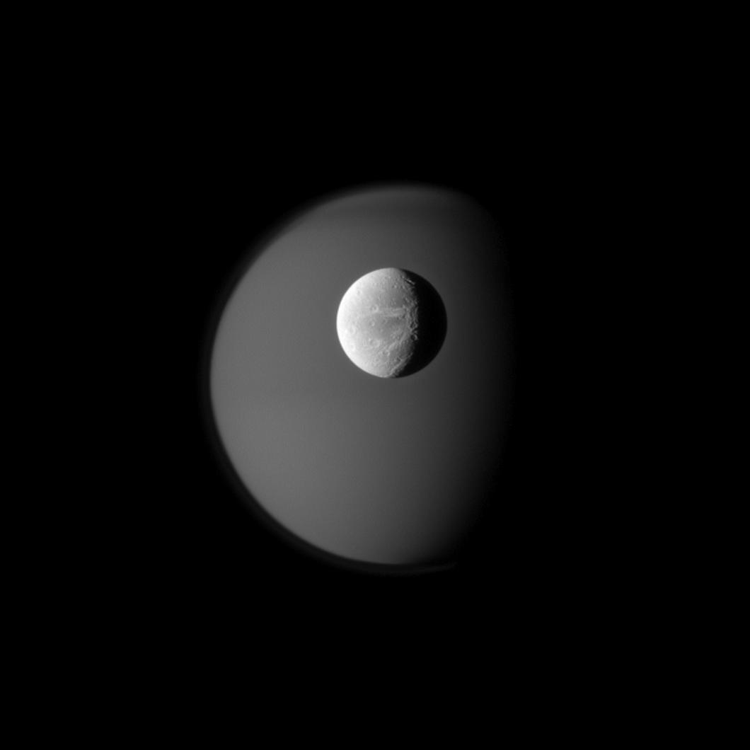 Dione in crisp detail against a hazy Titan