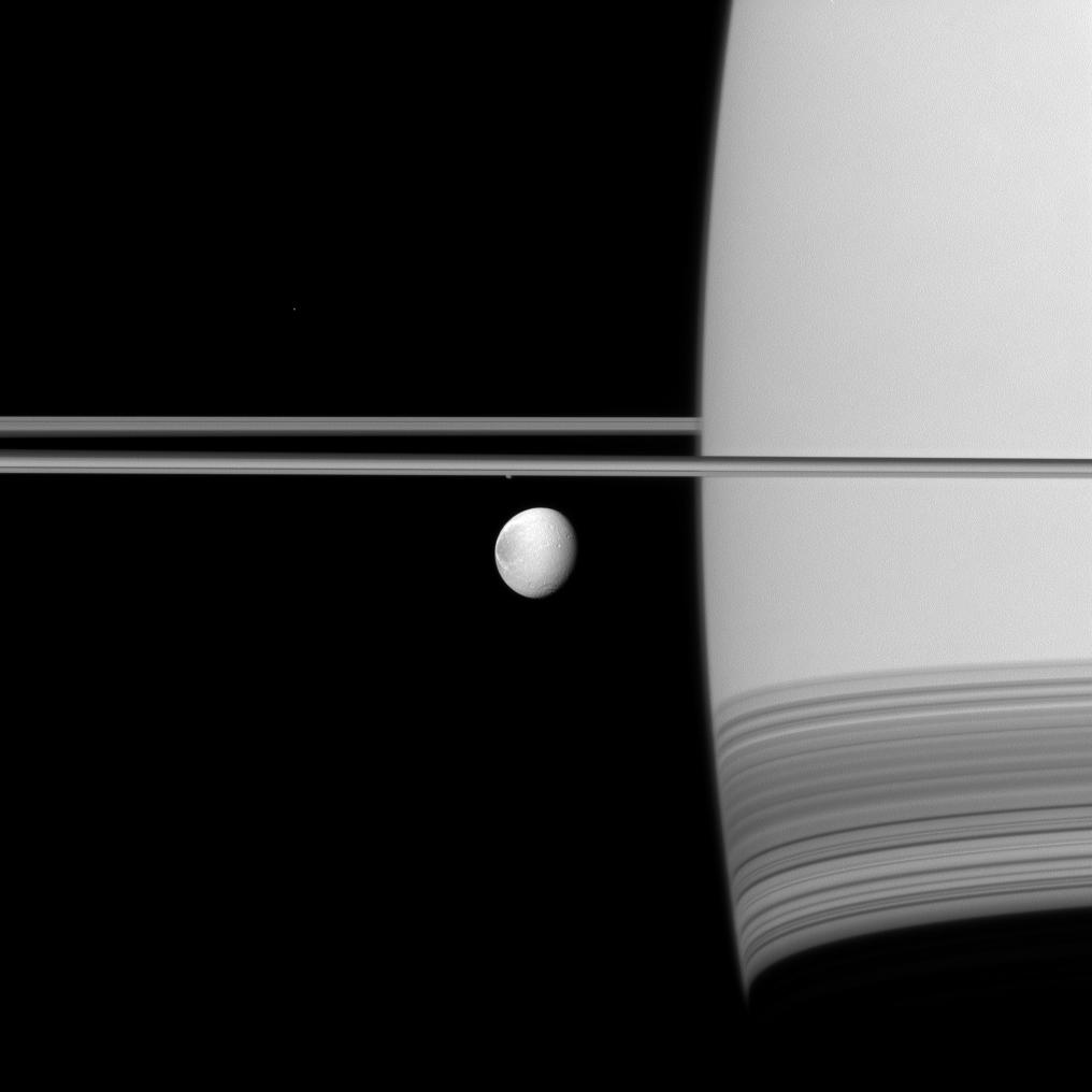 Saturn's moon Dione coasts along in its orbit appearing in front of its parent planet in this Cassini spacecraft view.