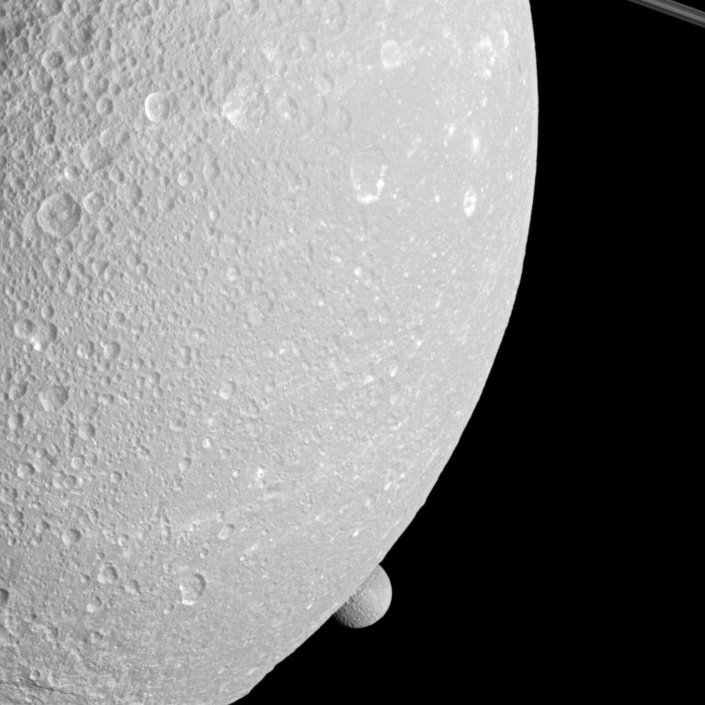 Saturn's moon Mimas peeps out from behind the larger moon Dione in this view from the Cassini spacecraft.