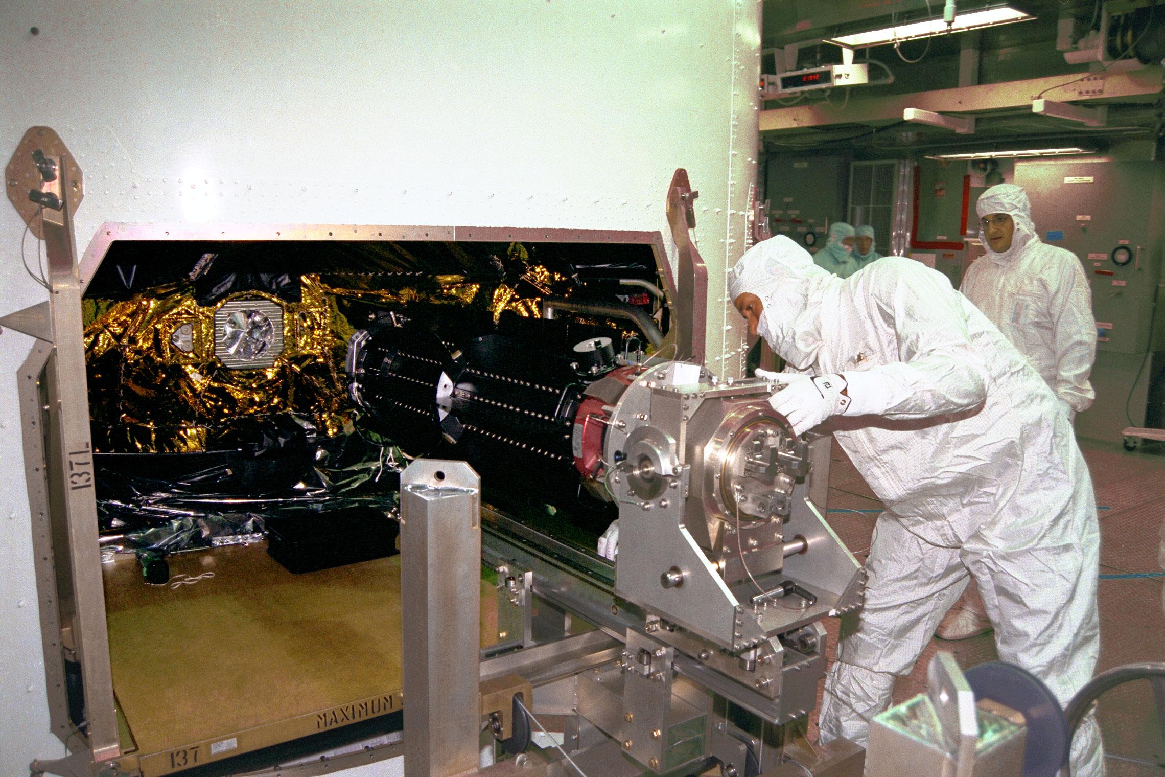 Man slides part into place on a spacecraft.