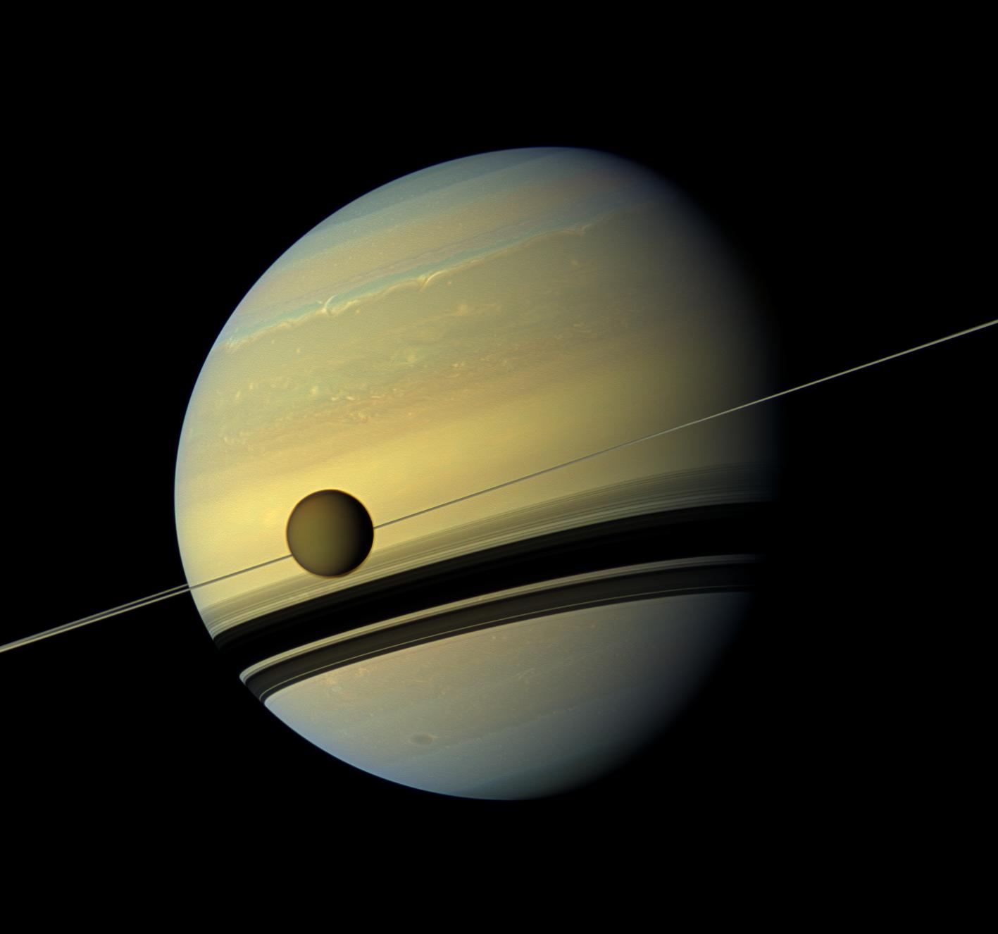 A giant of a moon appears before a giant of a planet undergoing seasonal changes in this natural color view of Titan and Saturn from NASA's Cassini spacecraft.