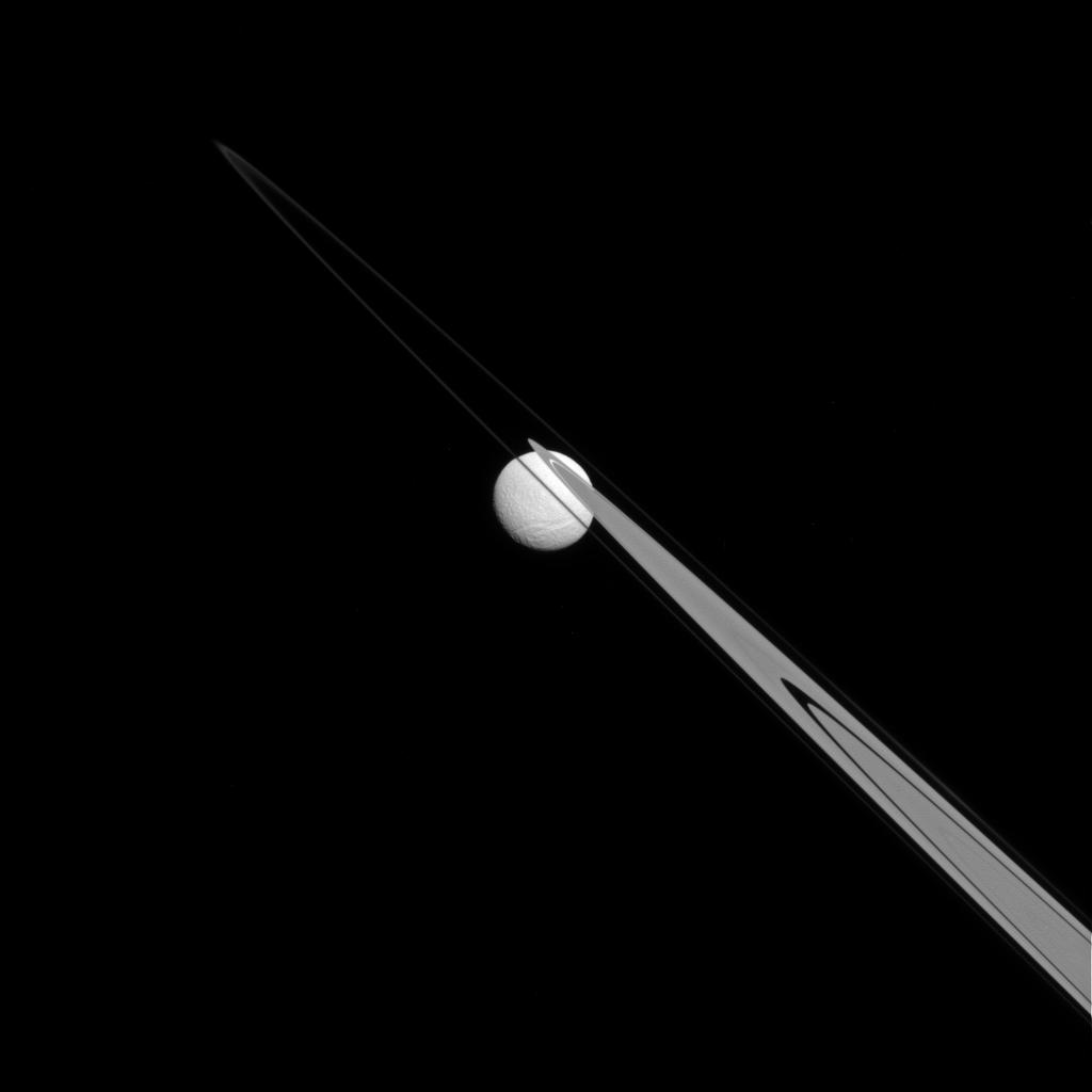 Like a drop of dew hanging on a leaf, Tethys appears to be stuck to the A and F rings from this perspective.