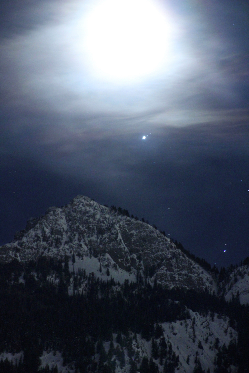bright, hazy moon and stars over mountain range
