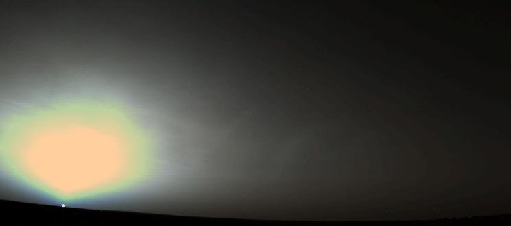 The small dot of the Sun peeks over a dark Martian horizon.