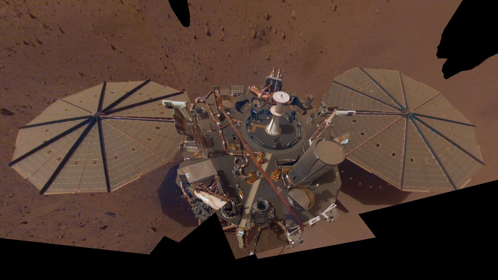 spacecraft on reddish surface, seen from above, covered in dust
