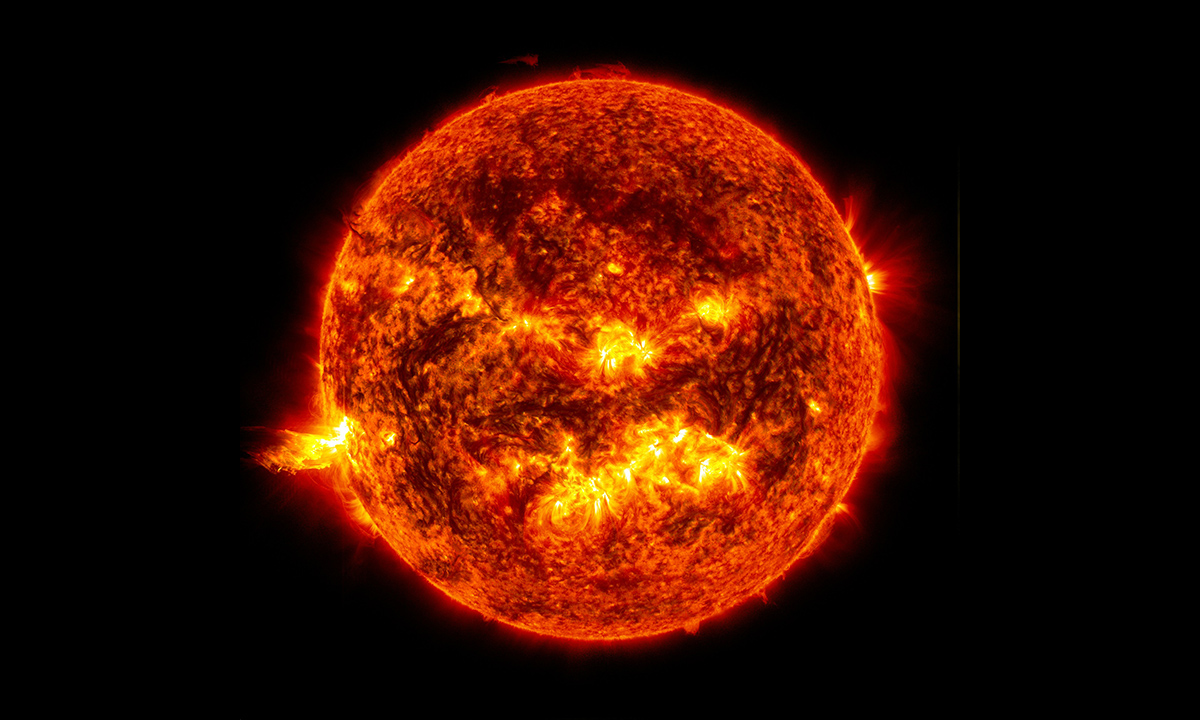 This image shows the bright light of a solar flare on the left side of the Sun and an eruption of solar material shooting through the Sun's atmosphere. 