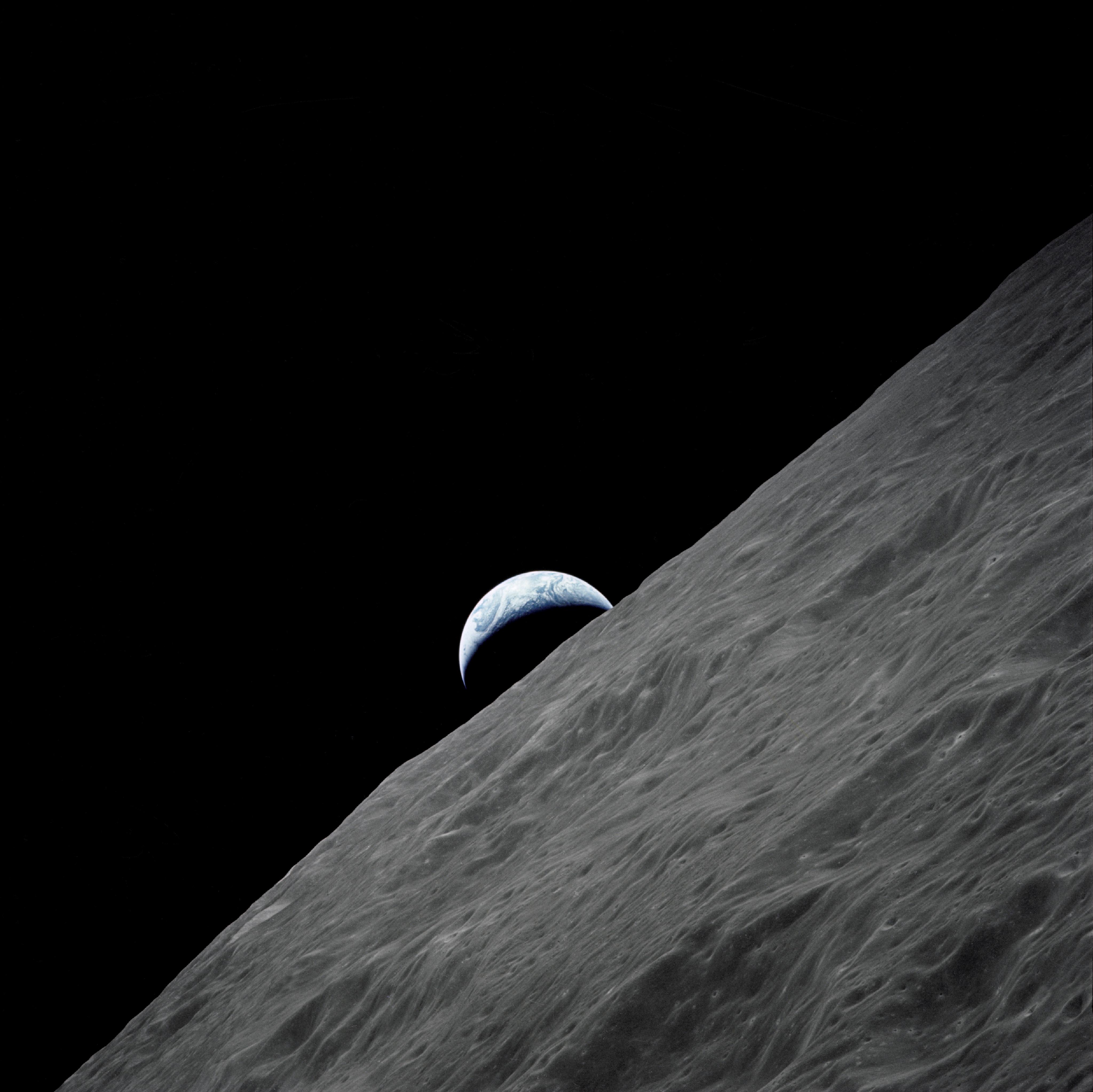 The crescent Earth rises above the lunar horizon in this spectacular photograph taken from the Apollo 17 spacecraft in lunar orbit during final lunar landing mission in the Apollo program.